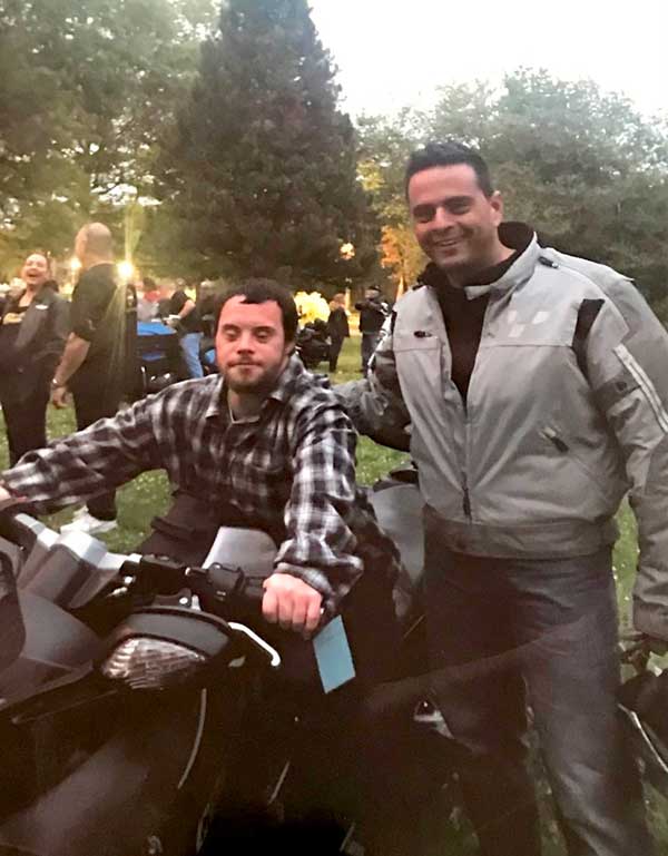 Photo of attorney Russo standing by a young man who is seated on a motorcycle